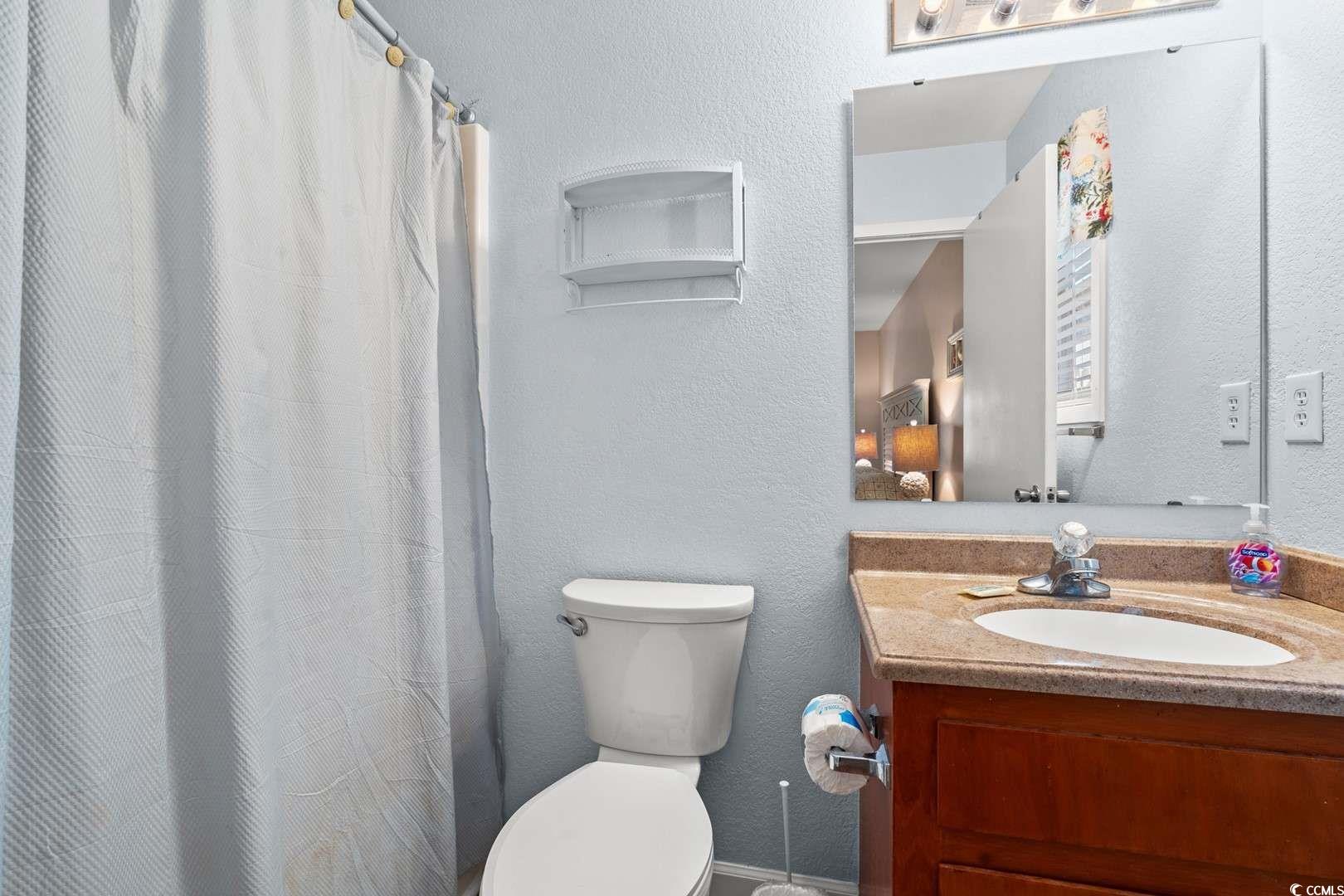 9500 Queens Court Myrtle Beach, SC 29572 - Photo 16 of 33 Full bath featuring toilet, a shower with curtain, vanity, and a textured wall