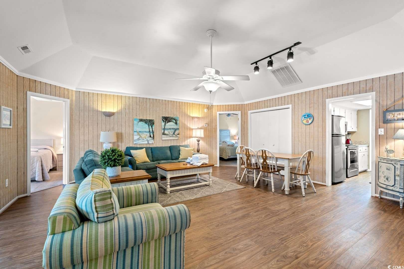 9500 Queens Court Myrtle Beach, SC 29572 - Photo 3 of 33 Living area with crown molding, ceiling fan, vaulted ceiling, visible vents, and wood finished floors