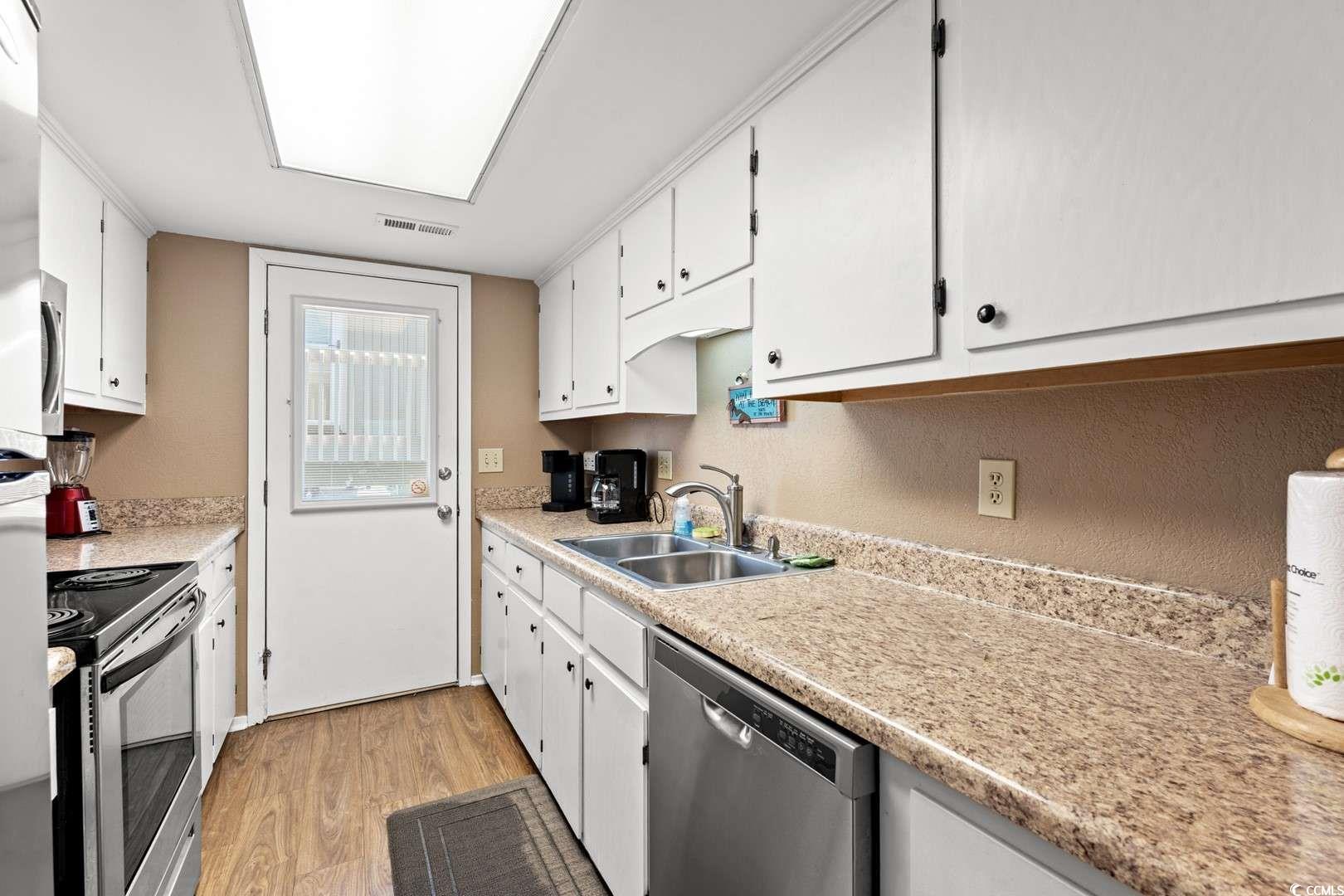 9500 Queens Court Myrtle Beach, SC 29572 - Photo 6 of 33 Kitchen with light wood-style flooring, white cabinets, visible vents, a sink, and stainless steel appliances