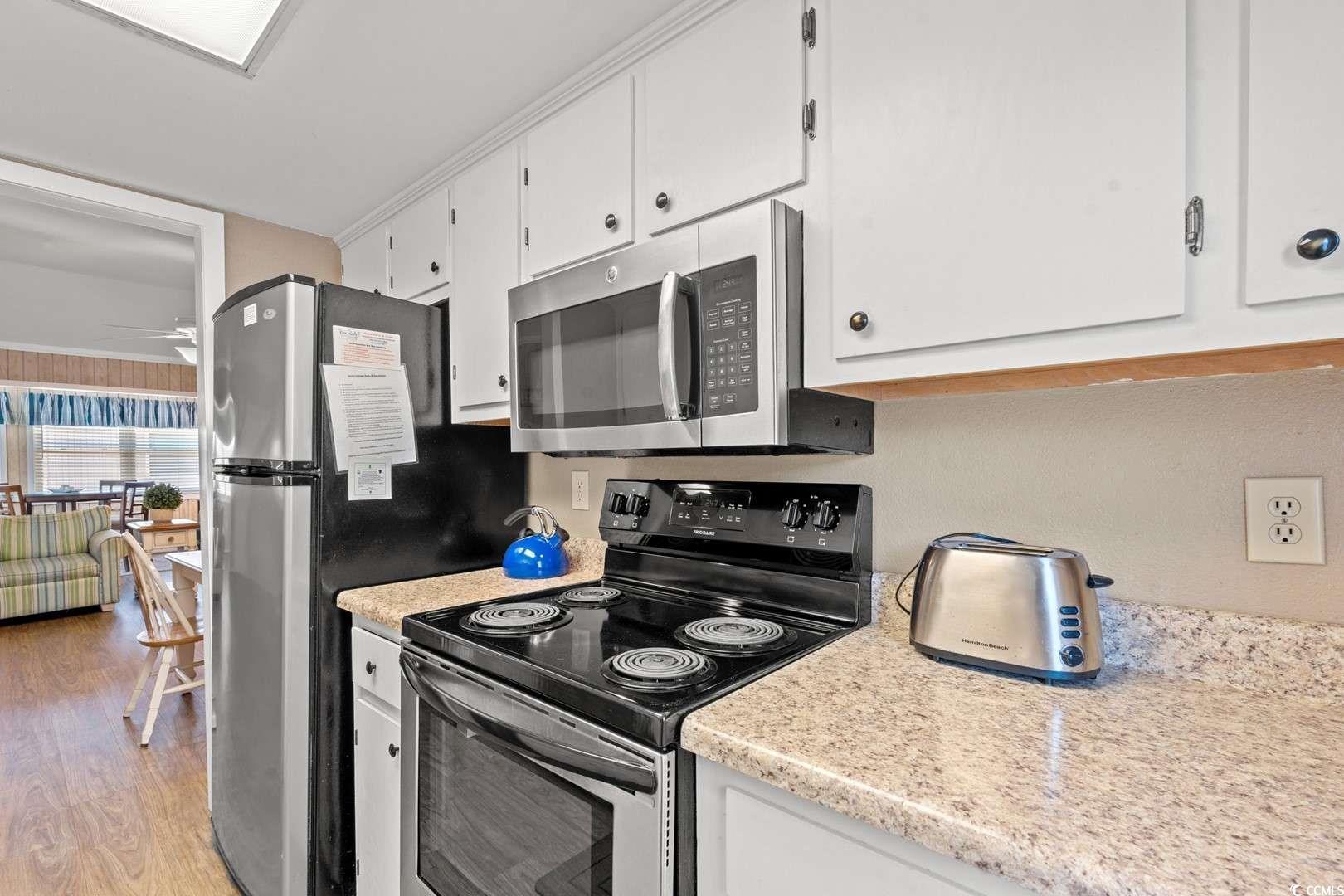 9500 Queens Court Myrtle Beach, SC 29572 - Photo 7 of 33 Kitchen featuring stainless steel appliances, light wood-type flooring, white cabinets, and light countertops
