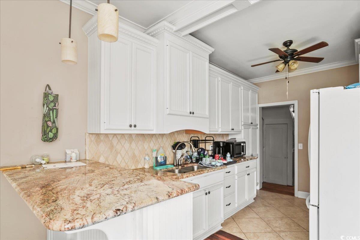 818 Evans Road Marion, SC 29571 - Photo 12 of 39 Kitchen featuring freestanding refrigerator, backsplash, white cabinets, and ornamental molding