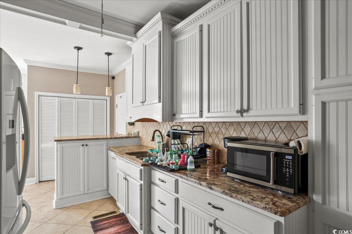 818 Evans Road Marion, SC 29571 - Photo 13 of 39 Kitchen featuring stainless steel appliances, crown molding, light tile patterned flooring, backsplash, and decorative light fixtures