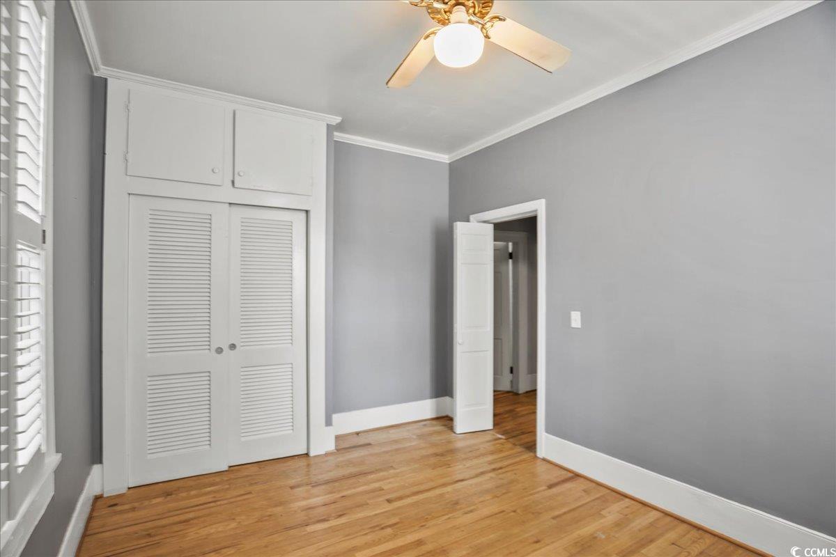 818 Evans Road Marion, SC 29571 - Photo 19 of 39 Unfurnished bedroom with crown molding, light wood finished floors, a ceiling fan, and a closet