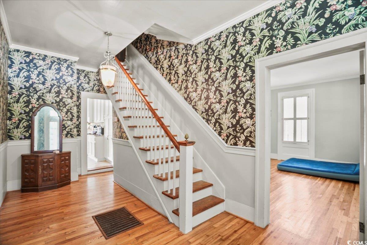 818 Evans Road Marion, SC 29571 - Photo 8 of 39 Staircase with wallpapered walls, ornamental molding, wood finished floors, and a wainscoted wall