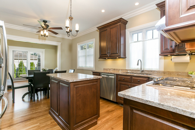 4553 Wolf Road Western Springs, IL 60558 - Photo 9 of 35 a kitchen with a stove a sink a dining table and chairs with wooden floor