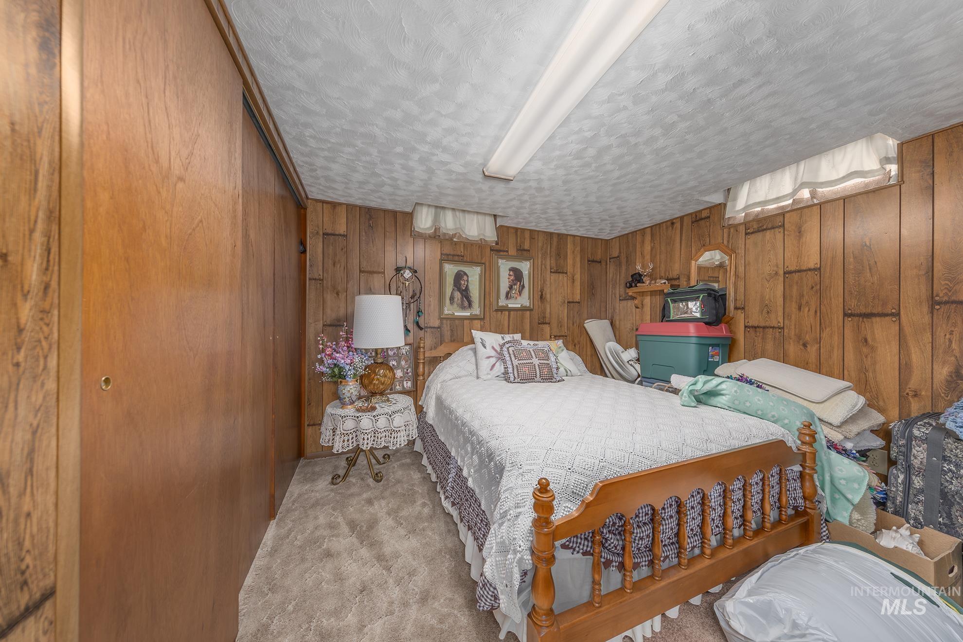 116 Pioneer Road Weiser, ID 83672 - Photo 23 of 41 Carpeted bedroom featuring wooden walls and a textured ceiling