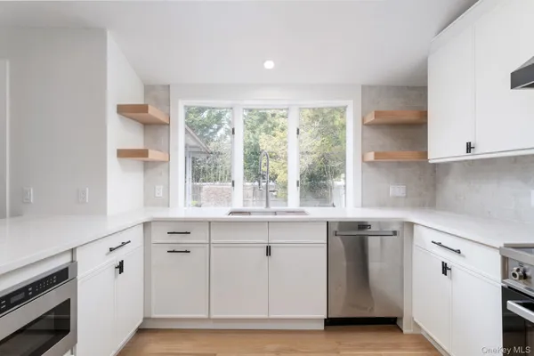 a kitchen with white cabinets and a window