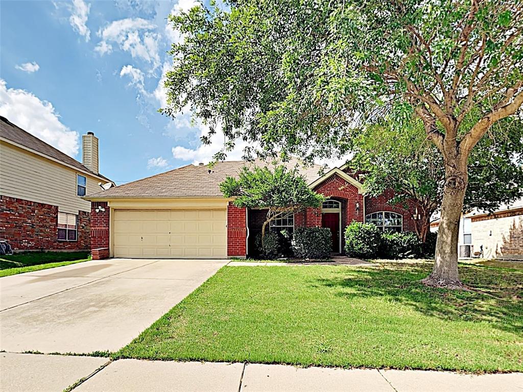 View of front of property with a garage, driveway, a front yard, and brick siding