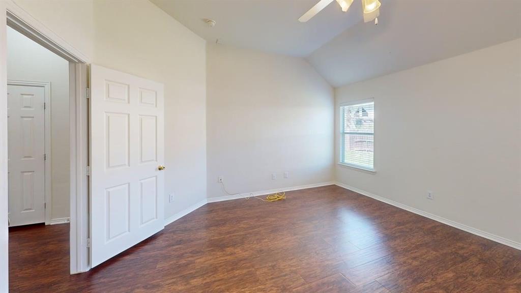 3223 Winding Ridge Circle Arlington, TX 76063 - Photo 11 of 27 Empty room featuring dark wood-type flooring, vaulted ceiling, and a ceiling fan
