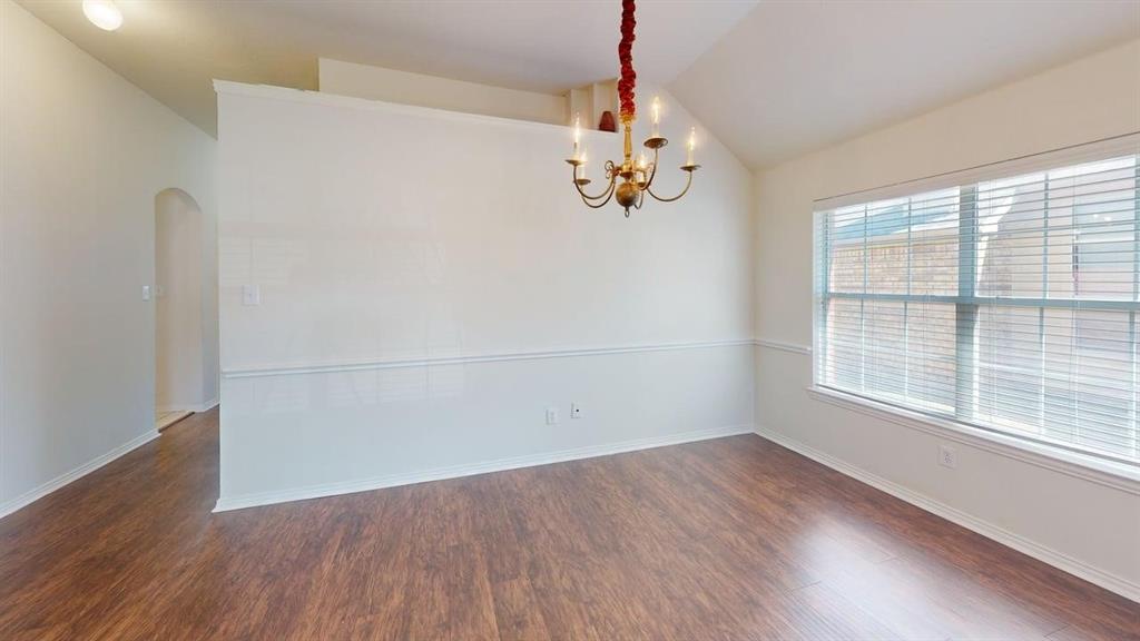 3223 Winding Ridge Circle Arlington, TX 76063 - Photo 7 of 27 Spare room featuring arched walkways, vaulted ceiling, dark wood finished floors, and hanging lights