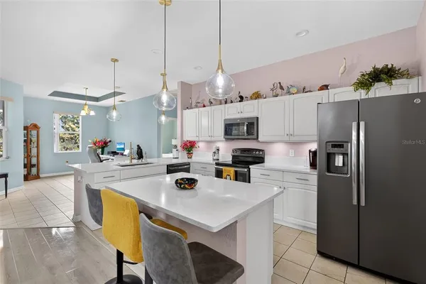 a kitchen with stainless steel appliances a stove a sink a refrigerator a center island a table and chairs