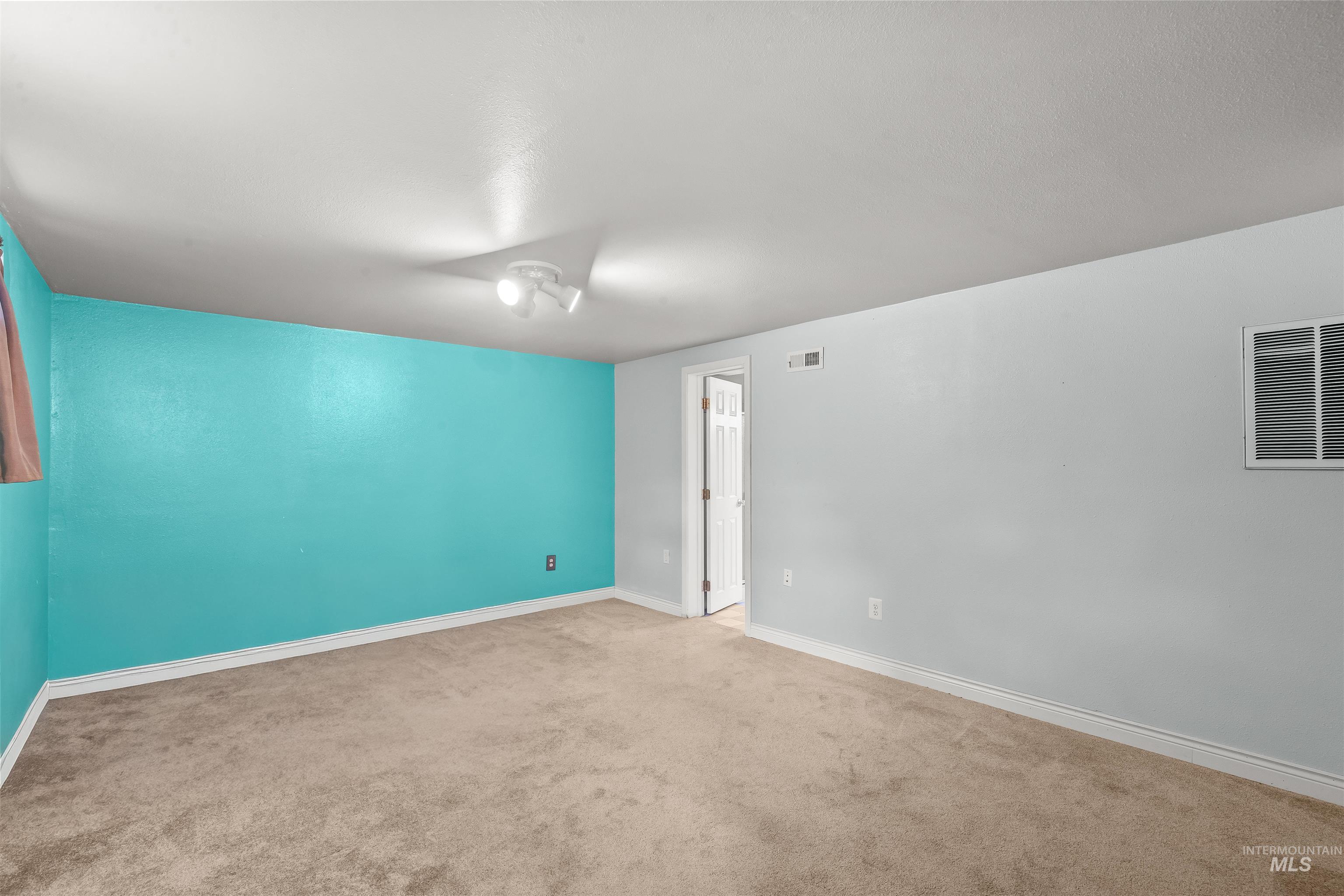 3620 18th Street Lewiston, ID 83501 - Photo 18 of 32 Spacious room featuring neutral carpet flooring, a vibrant accent wall, white trim, and a ceiling-mounted light fixture