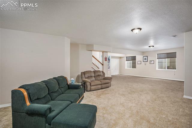 9709 Rockingham Drive Peyton, CO 80831 - Photo 28 of 50 Living area featuring stairs, a textured ceiling, carpet flooring, and baseboards