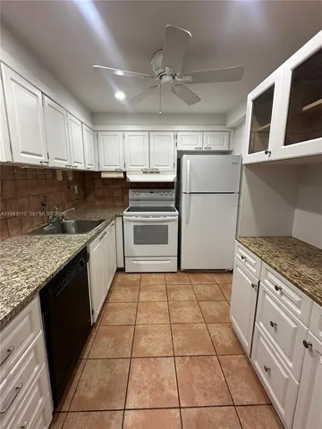 a kitchen with granite countertop a stove a sink and a refrigerator