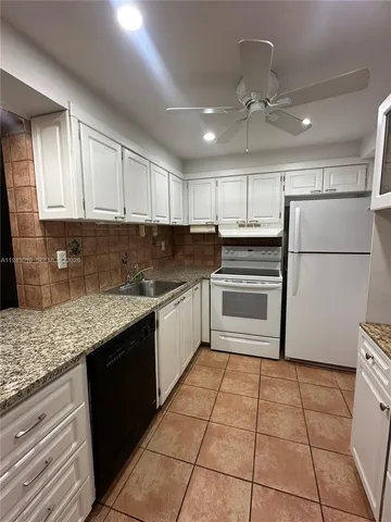 a kitchen with granite countertop a refrigerator and a sink