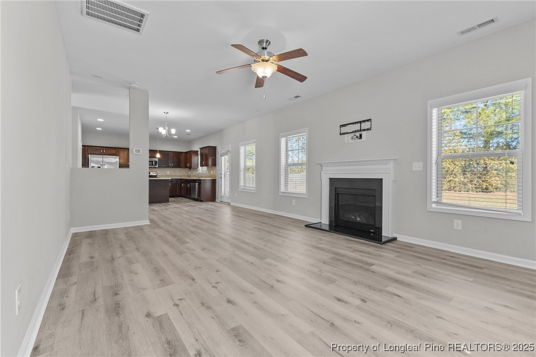 251 Crane Way Bunnlevel, NC 28323 - Photo 21 of 49 an empty room with fireplace wooden floor chandelier fan and windows