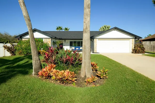 a front view of a house with a yard and potted plants