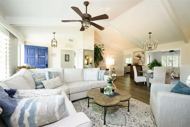 a living room with furniture kitchen view and a chandelier