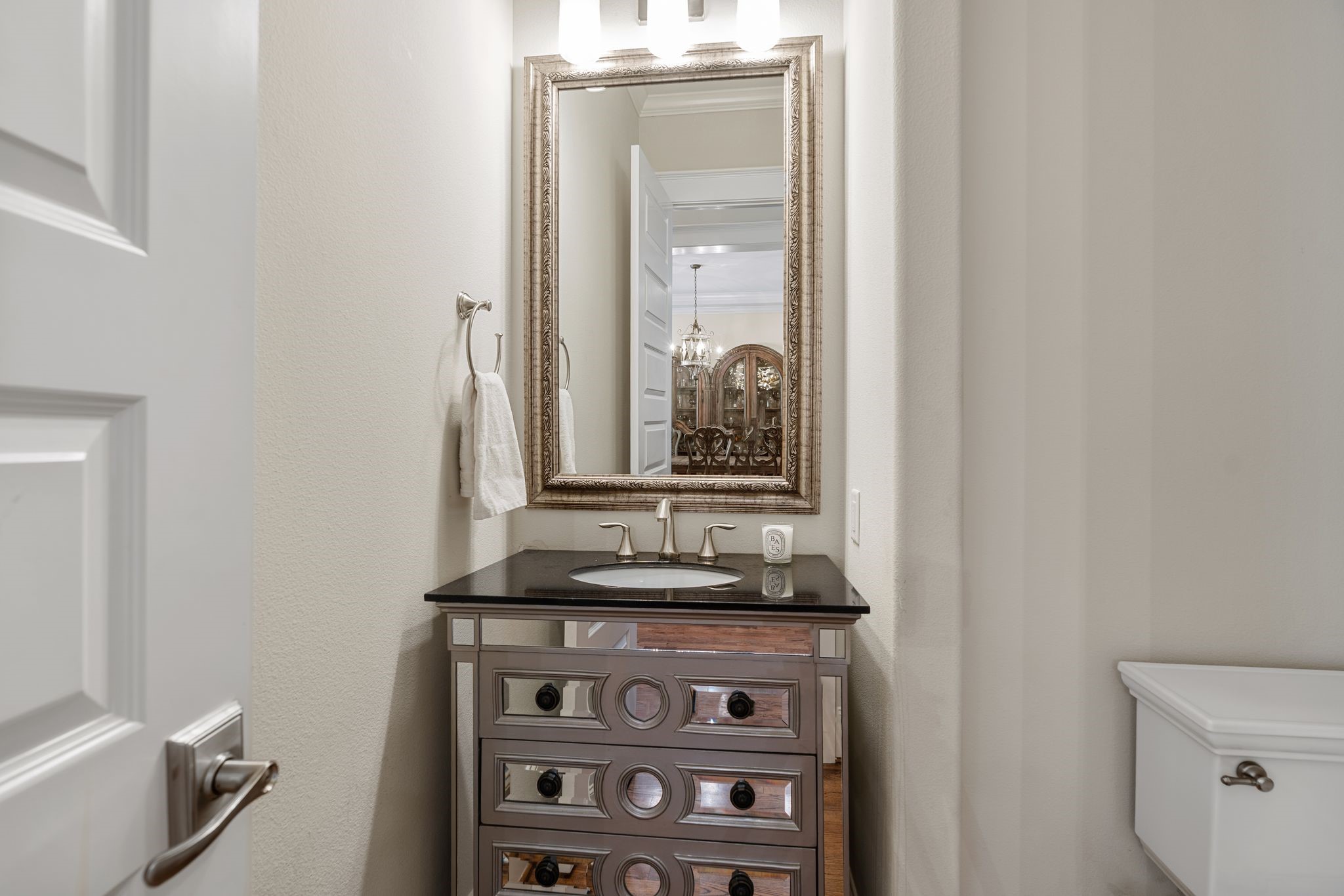 1217 Chippendale Road Houston, TX 77018 - Photo 22 of 42 Conveniently located off the entry & main living areas, the powder bath makes a stylish statement w/ a mirrored vanity featuring decorative detailing, oval undermount sink, & black stone countertop. A decorative framed mirror & vanity light fixture complete the space.
