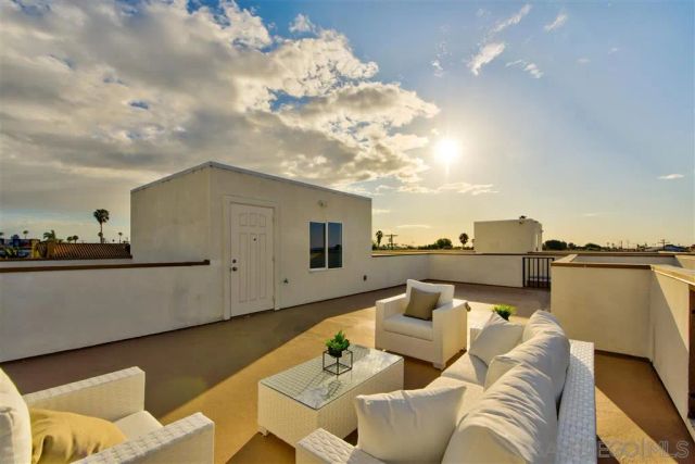 a roof deck with couches and potted plants with sky view