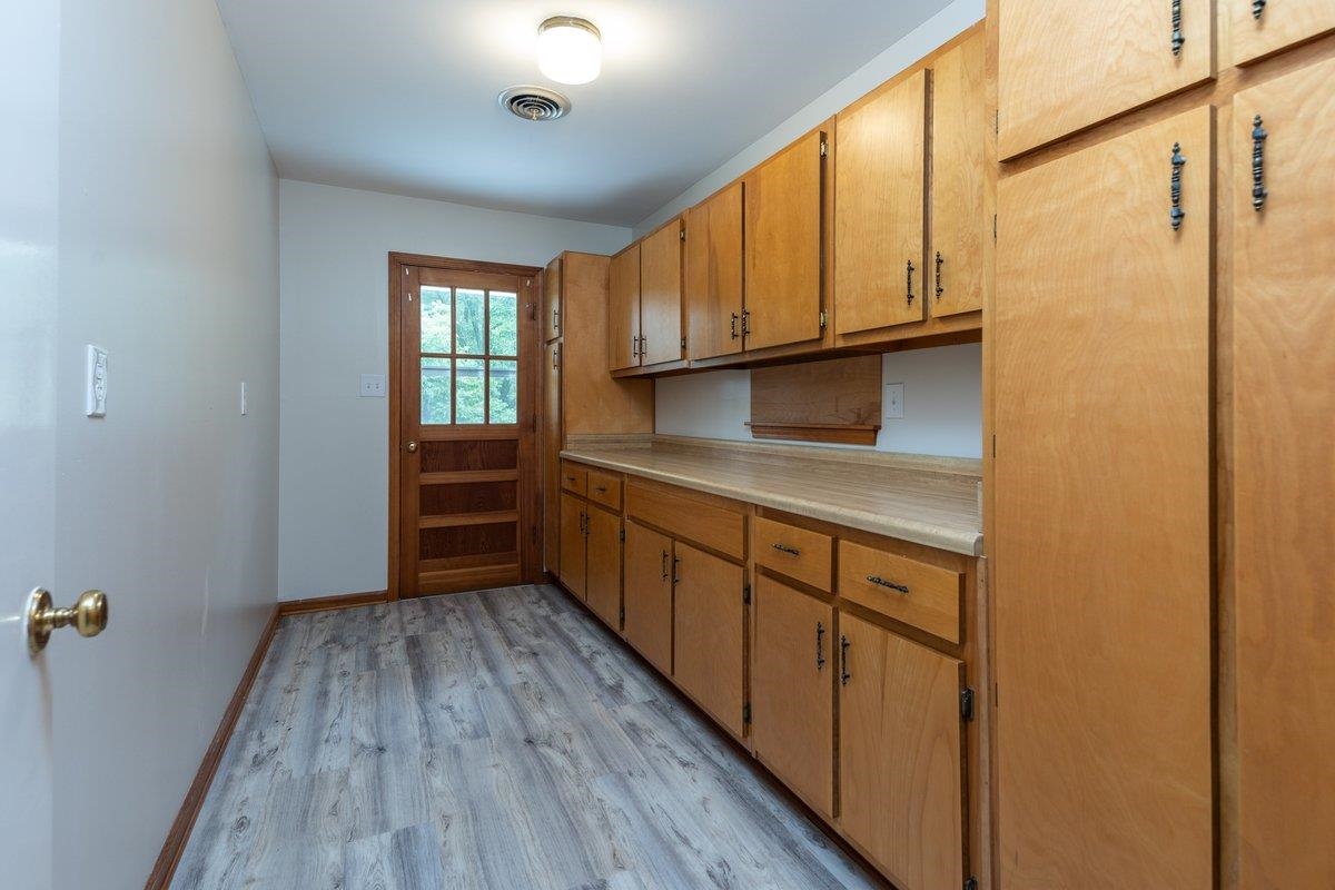 670 Peterson Lake Road Collierville, TN 38017 - Photo 17 of 37 Kitchen featuring extensive light wood cabinetry, laminate countertops, wood-finish flooring, and a glass-paneled door