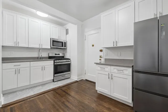 a kitchen with granite countertop white cabinets and stainless steel appliances