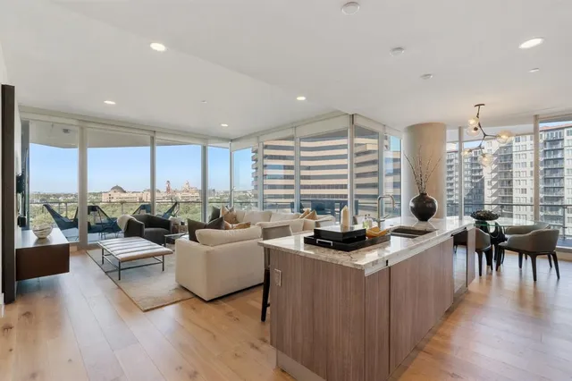 a living room with furniture large window and wooden floor