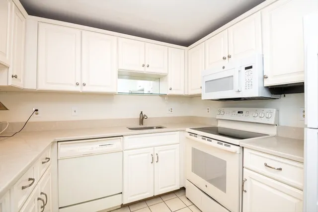 a kitchen with white cabinets and white appliances