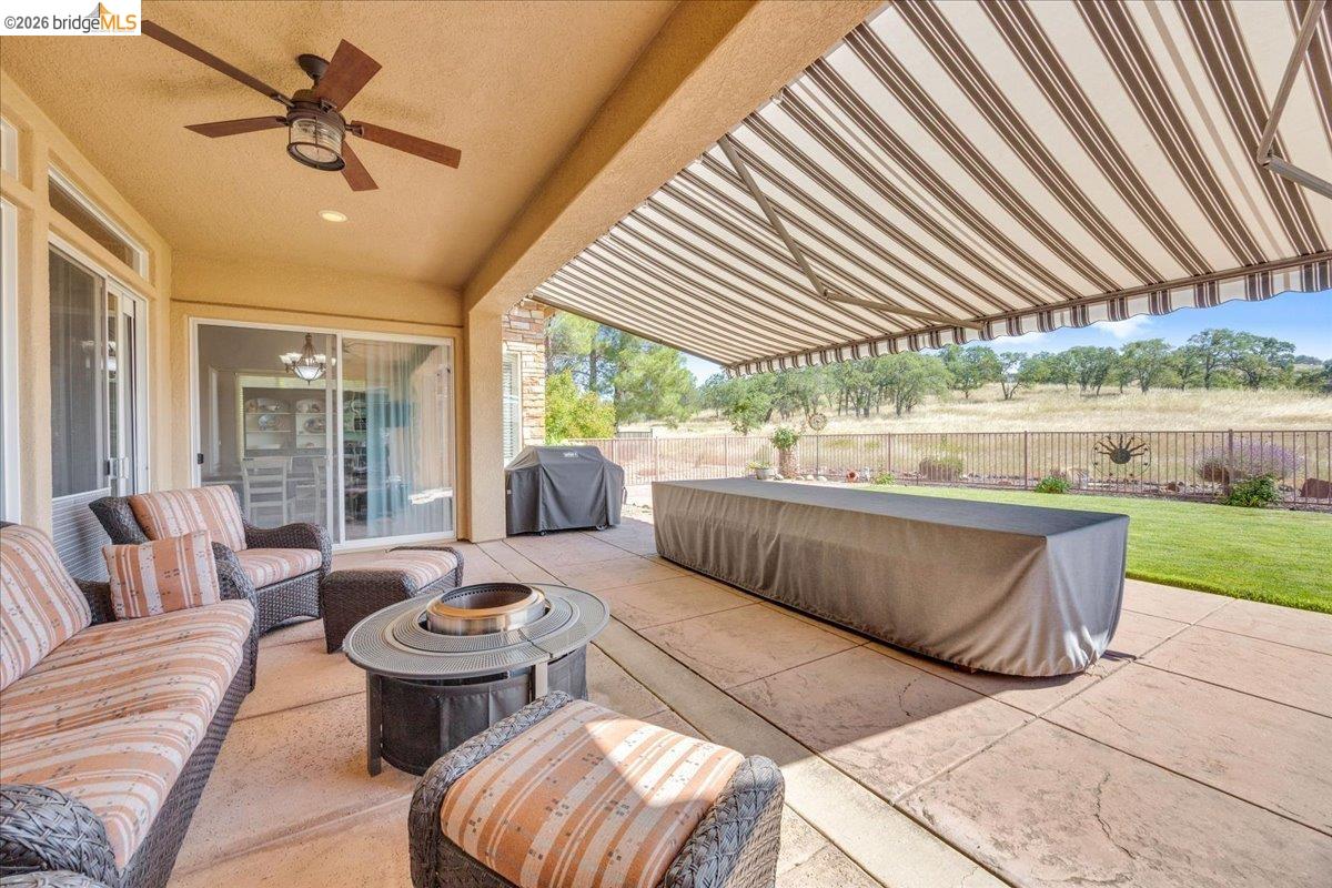 158 Rock Ridge Lane Copperopolis, CA 95228 - Photo 54 of 72 Expansive covered patio featuring stamped concrete flooring, a ceiling fan, and a retractable awning for versatile outdoor enjoyment