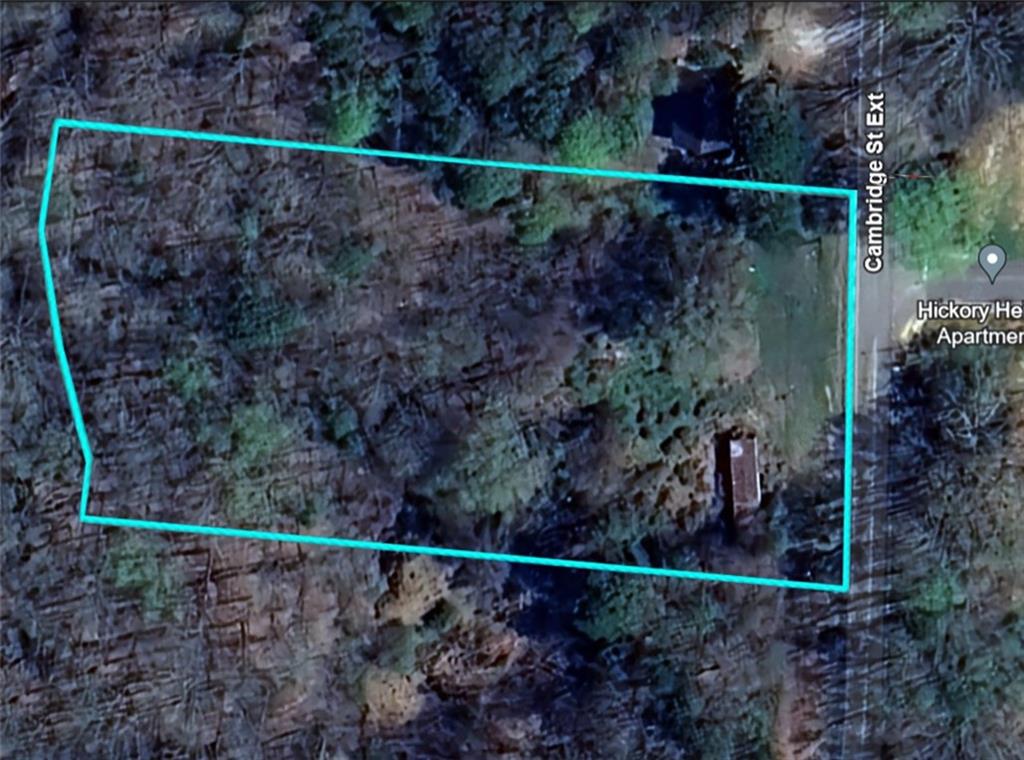 1125 Cambridge St Extension Abbeville, SC 29620 - Photo 1 of 7 This aerial view showcases a spacious, undeveloped parcel bordered by mature trees and a nearby road.
