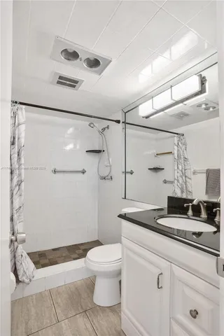 a bathroom with a granite countertop sink a toilet and shower
