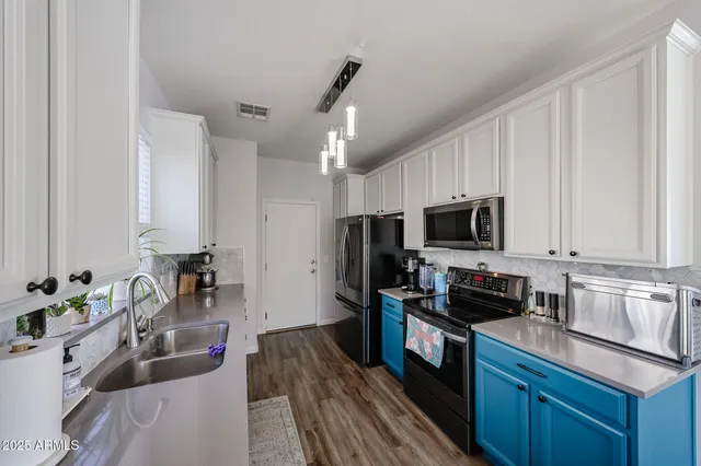 a kitchen with stainless steel appliances granite countertop a refrigerator a stove a sink dishwasher a dining table and chairs with wooden floor