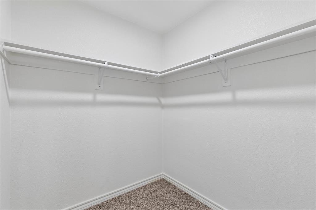 4725 St Lawrence Road Fort Worth, TX 76103 - Photo 13 of 26 Interior closet featuring white walls, carpeting, and a built-in white shelf with a hanging rod