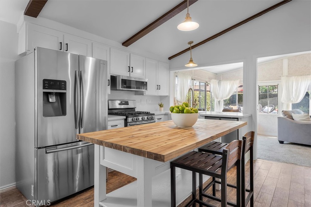 1702 East Dimondale Drive Carson, CA 90746 - Photo 14 of 43 a kitchen with stainless steel appliances a dining table chairs refrigerator and microwave