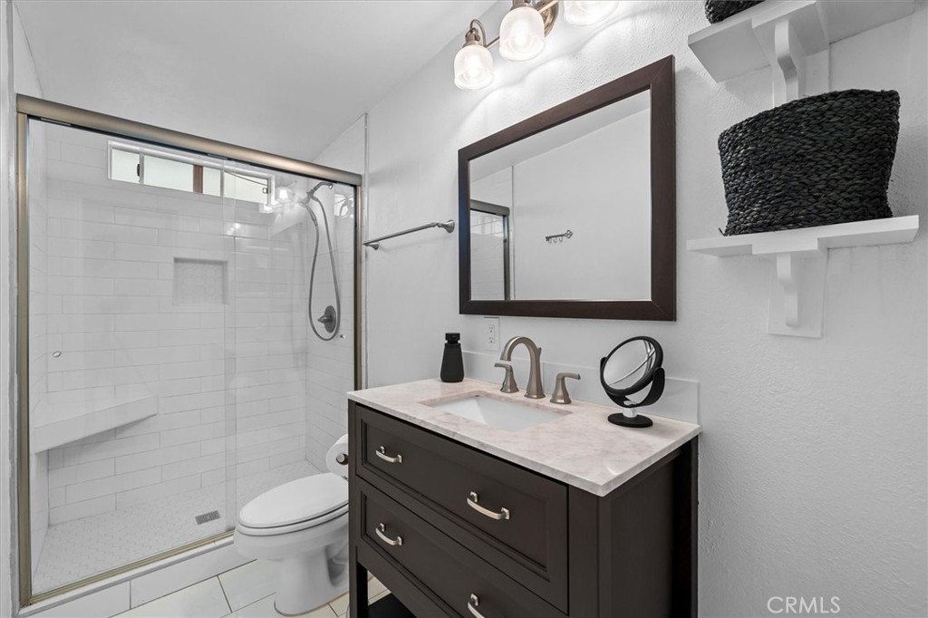 1702 East Dimondale Drive Carson, CA 90746 - Photo 33 of 43 a bathroom with a toilet a sink a mirror a shower and vanity