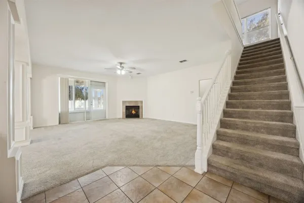 a view of an empty room with wooden floor and stairs