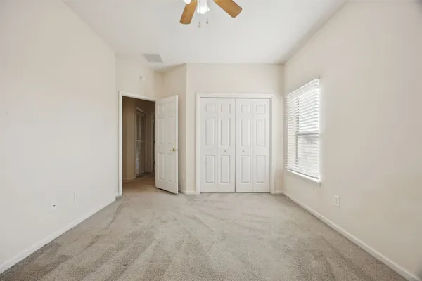 an empty room with chandelier fan and windows