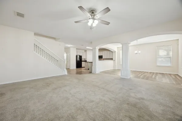 a view of an empty room with chandelier fan