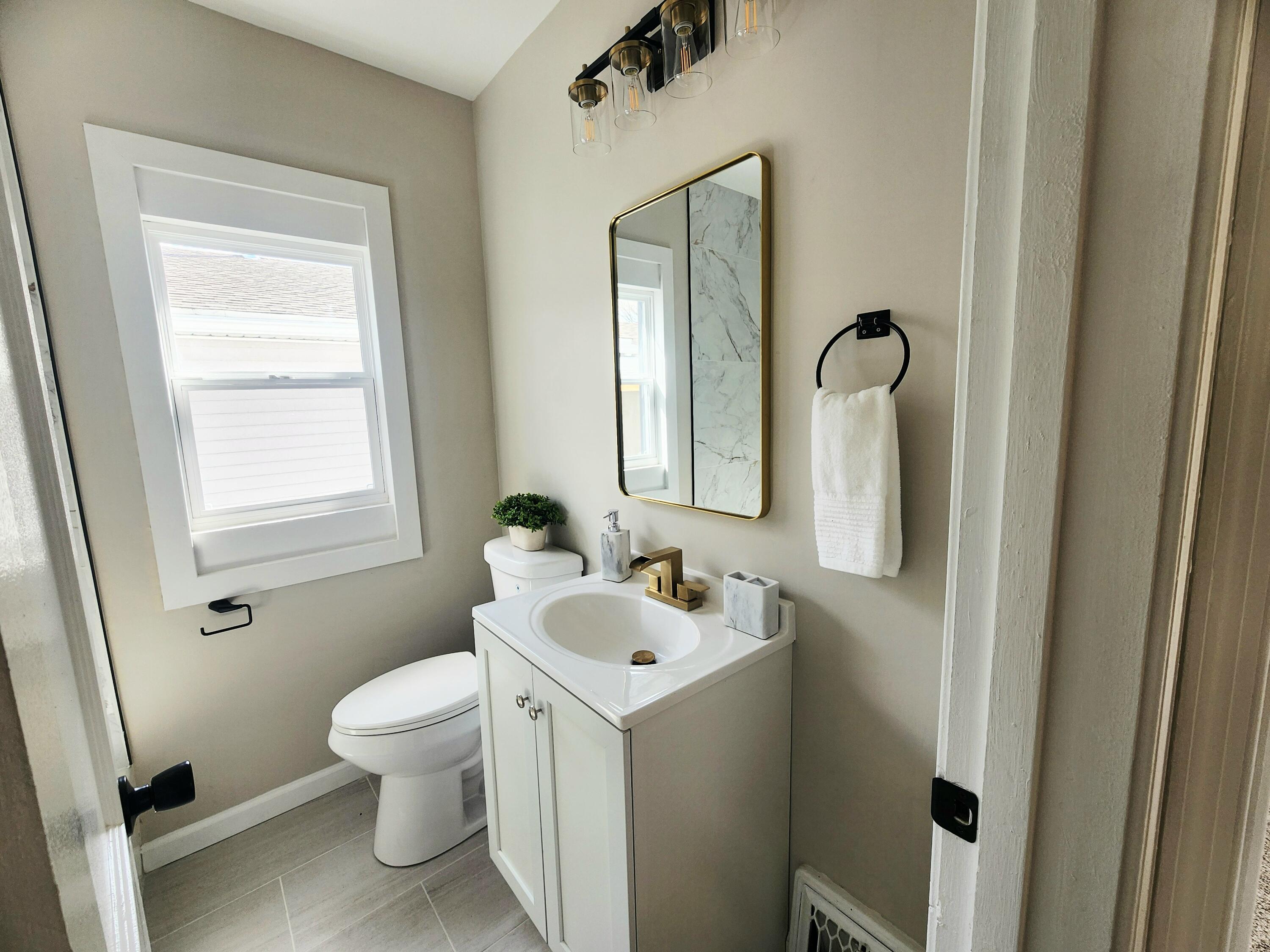 601 Burr Street Gary, IN 46406 - Photo 14 of 24 a bathroom with a toilet sink and mirror with window