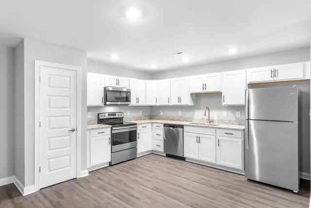 a kitchen with white cabinets stainless steel appliances and a refrigerator