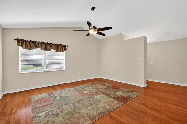 an empty room with wooden floor ceiling fan and window