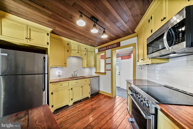 a kitchen with granite countertop a refrigerator a stove and wooden cabinets