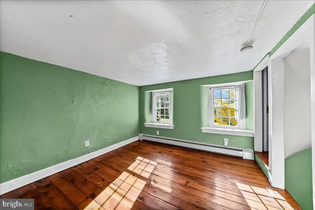 a view of empty room with window and wooden floor
