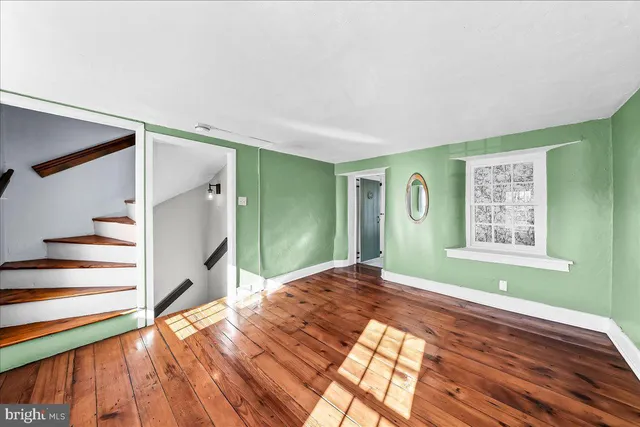 a view of an empty room with a window and wooden floor