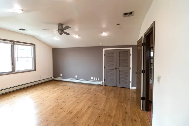 a view of an empty room with a window and wooden floor