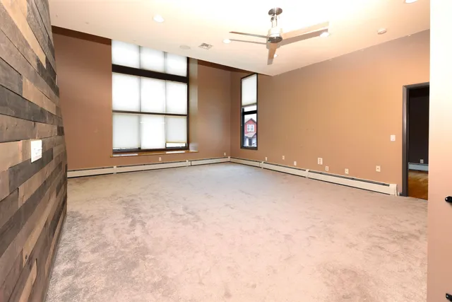 an empty room with windows and ceiling fan