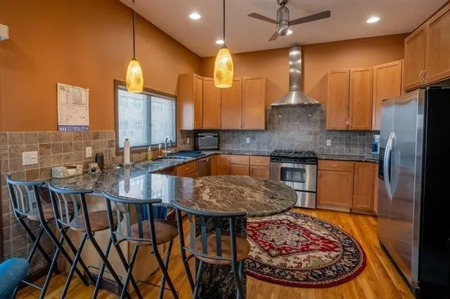 a kitchen with stainless steel appliances granite countertop a refrigerator a oven a sink dishwasher and couches with wooden floor