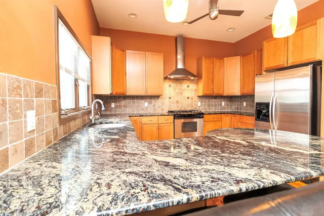 a large kitchen with kitchen island granite countertop a stove a sink and a refrigerator
