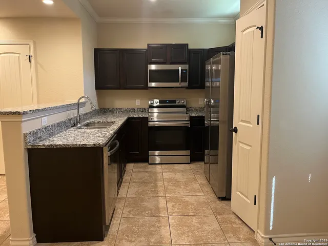 a kitchen with stainless steel appliances granite countertop a stove a sink and a microwave