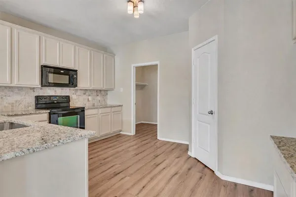 a kitchen with granite countertop white cabinets and stainless steel appliances